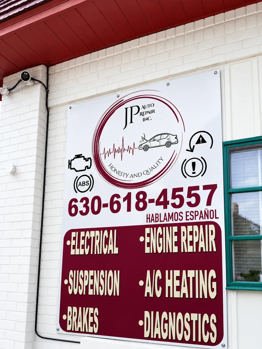 JP Auto Repair services sign — electrical, engine, brakes, A/C, diagnostics — se habla español